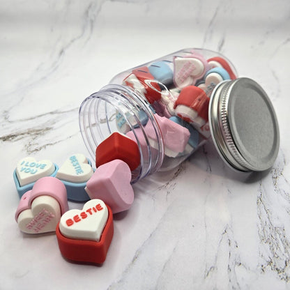 3D printed conversation heart fidget clickers spilling out of jar showing colorful hearts with messages like Bestie I Love You and Sweetheart Valentine's Day sensory toy gift clicky stress relief fidget toy
